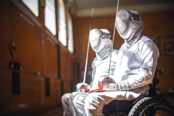 two disabled fencers in mask look at light