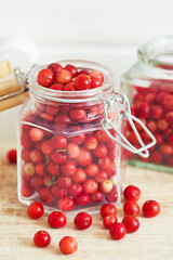 Fototapeta na wymiar Fresh ripe cranberries in glass jar on wooden background