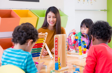 Asian female teacher teaching mixed race kids play toy in classroom,Kindergarten pre school concept