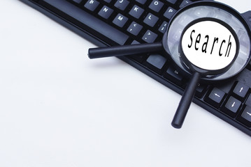 Magnifying Glass And Computer Keyboard Over White Background