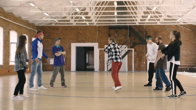 B-girl dances in front of her friends in sport gym