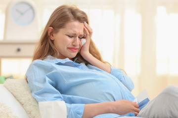 Beautiful pregnant woman crying in light room. Pregnancy hormones concept