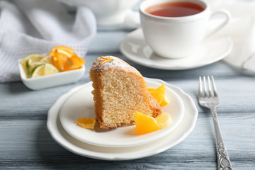 Plates with delicious cake and sliced citrus fruits on wooden table