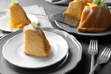Plate with delicious sliced citrus cake and orange on table