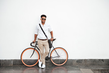 African man with bicycle standing over white wall