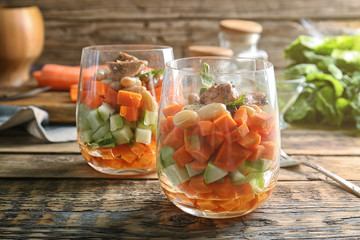 Glasses with delicious carrot salad on wooden table