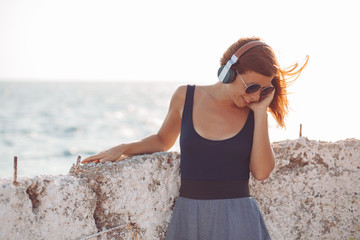 Young woman listening to the music on headphones by the sea