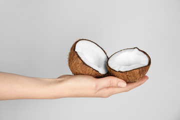 Female hand holding cracked coconut on grey background