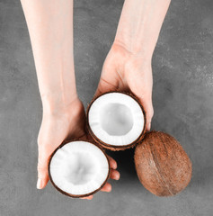 Female hands with coconuts on grey background