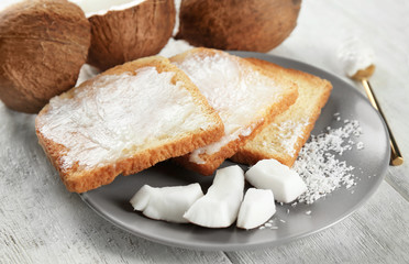 Delicious toasts with coconut oil in plate on table, closeup
