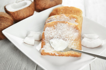 Delicious toasts with coconut oil in plate on table, closeup