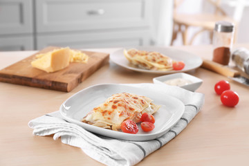 Composition with tasty lasagna, cheese and tomatoes on wooden table