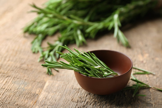 Bowl with fresh rosemary on table