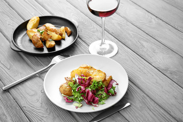 Tasty dinner with potato, mixed salad and glass of wine on table