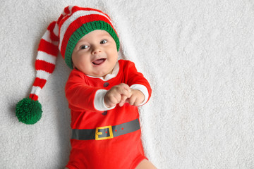 Cute little baby in Santa costume lying on soft fabric