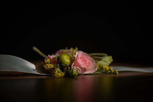 Wedding floral centerpiece with pink rose at its core against a dark background.