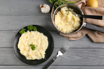 Plate and pot with mashed potatoes on wooden background