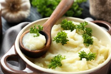 Casserole and wooden spoon with mashed potatoes on table, closeup