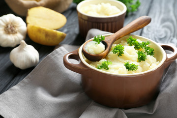 Casserole and wooden spoon with mashed potatoes on table