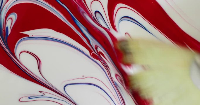 Using a wide fan paintbrush to make an abstract painting with red white and blue poster paint.
