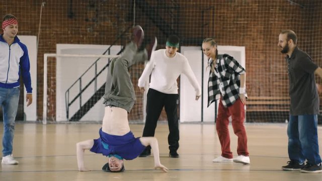 Breakdancer shows his moves as friends cheer him on. Slow motion