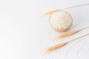 raw rice in a bamboo basket with wheat isolated on white background