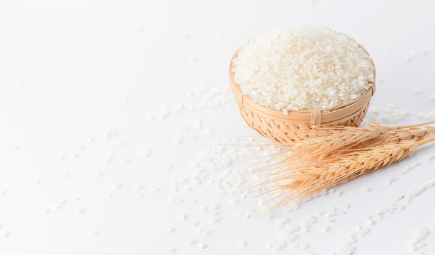 raw rice in a bamboo basket with wheat isolated on white background