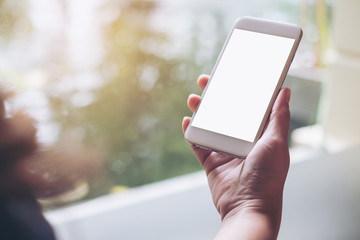 Mockup image of hands holding and using white smart phone with blank screen with pond and nature background