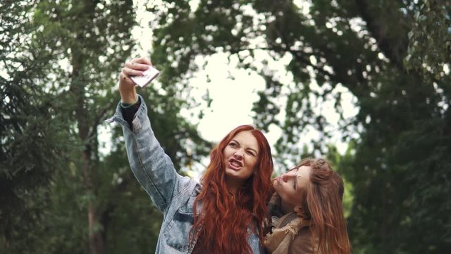 Redhead Friends taking selfie with a smart phone and making faces and fun. 20s