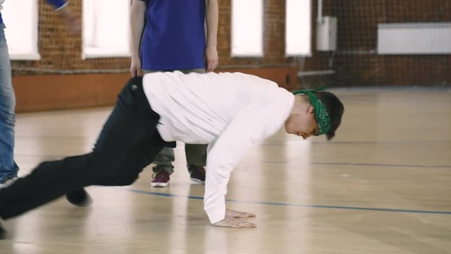 Breakdancer shows his moves as friends cheer him on. Slow motion