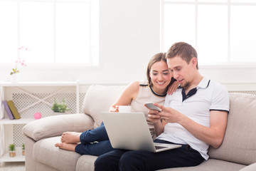 Young couple web surfing on laptop, copy space