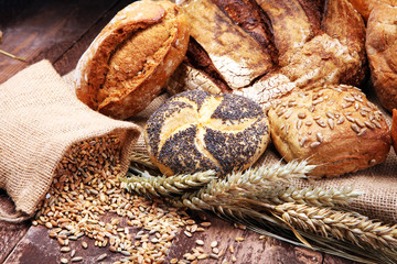 Different kinds of bread and bread rolls on wooden table