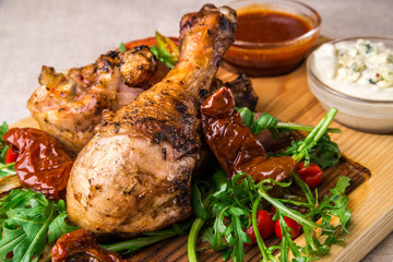 Appetizing fried chicken drumsticks, decorated with herbs, with sauces. Horizontal frame