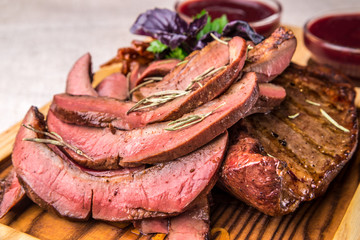 Sliced appetizing grilled tongue, decorated with herbs. Horizontal frame