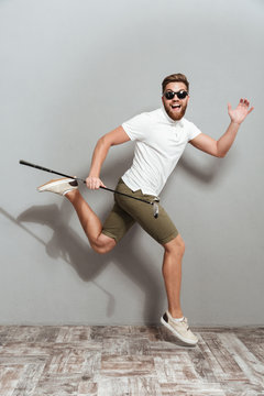 Full length image of a Happy funny golfer in sunglasses