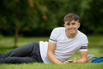 Naklejka na ściany i meble Teenage boy laying on grass on a summers day