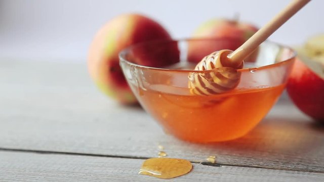 Movie of honey dripping. Apples on wooden table. Traditional celebration food for the Jewish New Year. Concept Rosh Hashana