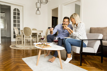 Young couple enjoying eating pizza and watching tv