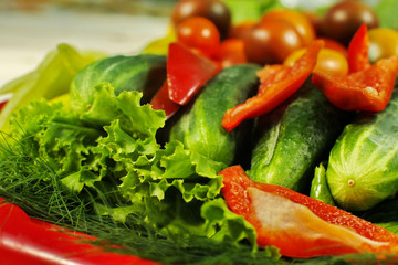 Assorted raw organic vegetables for healthy eating. Tomatoes, cucumbers, peppers and lettuce close up.