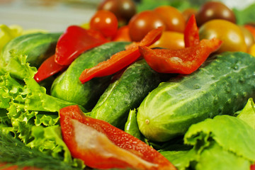 Assorted raw organic vegetables for healthy eating. Tomatoes, cucumbers, peppers and lettuce close up.