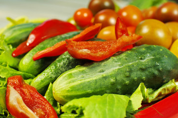 Assorted raw organic vegetables for healthy eating. Tomatoes, cucumbers, peppers and lettuce close up.