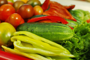 Assorted raw organic vegetables for healthy eating. Tomatoes, cucumbers, peppers and lettuce close up.