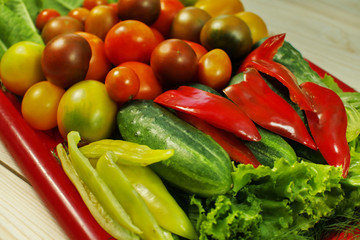 Assorted raw organic vegetables for healthy eating. Tomatoes, cucumbers, peppers and lettuce close up.
