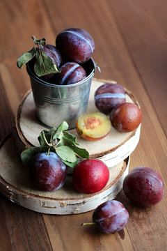 Plums in a small bucket on a wooden background
