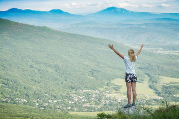 Happy woman standing on a cliffs edge