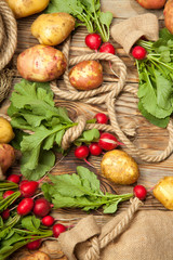 Potatoes and radishes on a wooden background