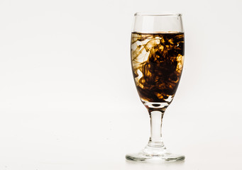 Dark brown food coloring diffuse in water inside wine glass with empty copyspace area for slogan or advertising text message, over isolated grey background. 