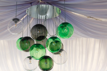 Fototapeta na wymiar Round lampshades of green and gray lamps hang on the ceiling