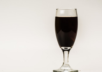 Dark brown food coloring diffuse in water inside wine glass with empty copyspace area for slogan or advertising text message, over isolated grey background. 