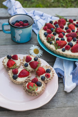 Fruit tart strawberries, blueberries, raspberries on wood in the garden view from above